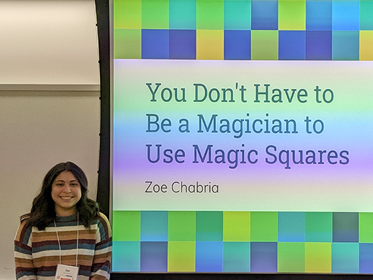 Zoe Chabria  giving her presentation in front of a colorful title screen that says You Don't Have to Be a Magician to Use Magic Squares.