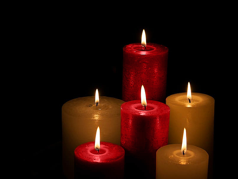Lit red and gold candles on a black backhround.