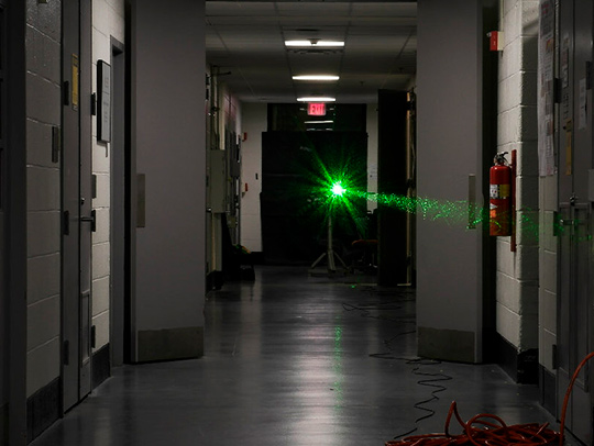 A green laser shoots down a long, dark hallway on the UMD campus.