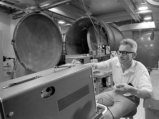 A black and white photo of the late Joseph Weber in his lab