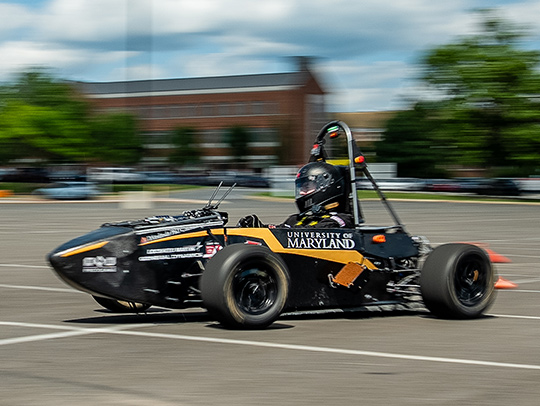 A member of Terps Racing driving the team's racecar through a parking lot on campus. Credit: Mark Sherwood.